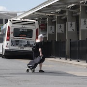 Une femme âgée marche près d'une gare d'autobus.