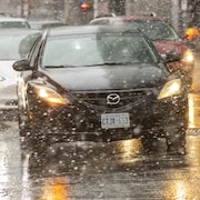 Des voitures, sous une neige légère, à l'angle des rues Front et Simcoe à Toronto.