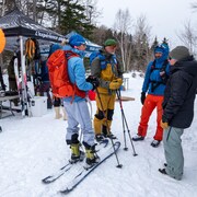 Des sportifs d'hiver équipés pour le ski devant les chapiteaux de l'événement d'Avalanche Québec.