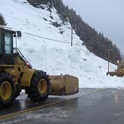 Camions qui déneigent la route obstruée par une avalanche.
