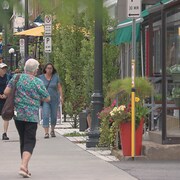 Des passants marchent sur le trottoir de l'avenue Maguire à Québec.  