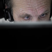 Un homme aveugle porte un casque d'écoute et travaille devant un ordinateur. 