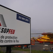 Deux avions-citernes sur le tarmac de l'aéroport de Val-d'Or. Une pancarte annonce les bureaux de la Société de protection des forêts contre le feu.