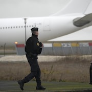 Un gendarme marche à proximité d'un avion.
