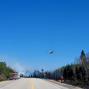 Un avion en approche d'un feu de forêt près d'une route.