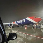 Un avion aux couleurs de l'équipe des Patriots de la Nouvelle-Angleterre est posé sur le tarmac d'un aéroport la nuit.