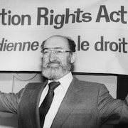 Le Dr Morgentaler se tient devant une bannière pro-choix.