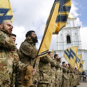 Des volontaires ukrainiens du bataillon Azov forment un rang avec leurs drapeaux.