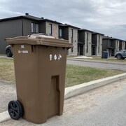 Des bacs bruns sur le bord d'une rue de Trois-Rivières.