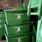 Des bacs de plastique verts empilés dans ce qui semble être un entrepôt.