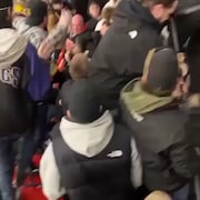 Une foule avec des gens s'échangeant des coups.