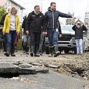 Les trois marchent dans une rue endommagée.