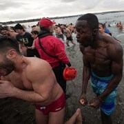 Des baigneurs réagissent au froid en sortant de l'eau lors du bain du Nouvel An an dans la baie des Anglais.