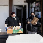 Deux femmes préprarent des boîtes de produits alimentaires.