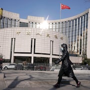 Une femme portant un masque passe devant un immeuble d'une institution bancaire chinoise.