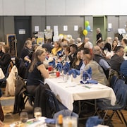 Un grand nombre de personnes assises à des tables pendant une célébration. 