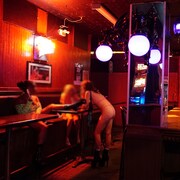 Des danseuses dont les visages sont flous attablées à l'intérieur d'un bar.