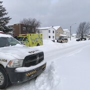 Trois voitures de la Sûreté du Québec et une ambulance sont stationnés sur une rue enneigée. 