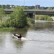 Un homme patrouille dans la rivière Saint-Charles à bord d'un bateau pneumatique.