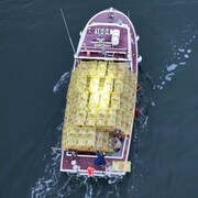 Vue de drone d'un bateau chargé et trois pêcheurs. 