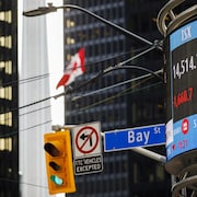 Un tableau électronique affiche les titres boursiers dans le quartier de la finance de Toronto. 