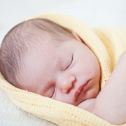 Un nouveau-né dort, enveloppé dans une couverture.