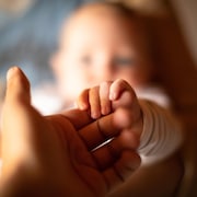Une main d'adulte tenant celle d'un nouveau-né.