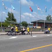 De jeunes bénévoles accompagnent des personnes en fauteuil roulant sur la promenade du Saint-Maurice à Shawinigan.