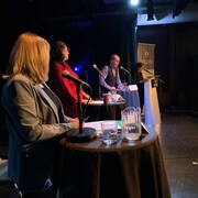 Steve Corriveau parle au micro lors d'un débat. Sylvie Bérubé, Mandy Gull-Masty et Émélie Rivard-Boudreau l'écoutent.