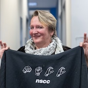Beverly Buchanan tient un chandail montrant NSCC en langage signé.