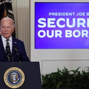 Joe Biden prend la parole devant un écran où on peut lire: «Le président Joe Biden protège notre frontière».