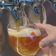 Une main tient un verre à bière en train d'être rempli.