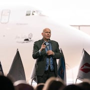 Dave Calhoun speaks to Boeing executives and employees in front of the plane.