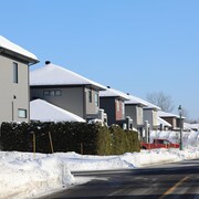 Des maisons semblables sur une rue résidentielle enneigée.