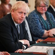 Boris Johnson est assis, les bras croisés, entouré de membres de son cabinet.
