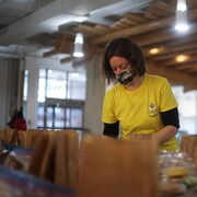Une bévévole de l'organisme La Boussole prépare des sacs de denrées alimentaires. 