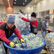 Des personnes trient des bouteilles.