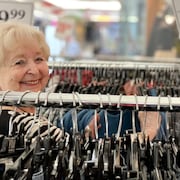 Une dame sourit dans un un magasin de vêtements