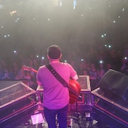 Brandon Girouard guitare à la main avec un groupe de festivalier allumant leur lumière au rythme d'une balade