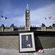 Un portrait encadré de l'ancien premier ministre Brian Mulroney est adossé à la Flamme du centenaire sur la colline du Parlement, à Ottawa. 