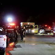 Divers véhicules d'urgence sont arrêtés dans la rue, la nuit.     