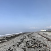 Une plage où on devine des silhouettes de personnes dans la brume.