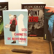 Les quatre livres sont rassemblés, debout, sur une boîte de bois.