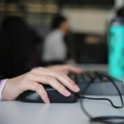 Une main sur une souris d’ordinateur.