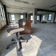 Un chaise et un bureau abandonnés dans une salle vide et poussiéreuse.