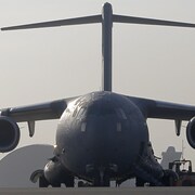 Deux militaires marchent vers un avion photographié de face. 