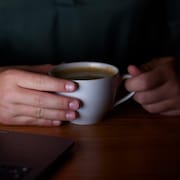 Une personne tient une tasse de café entre ses mains.