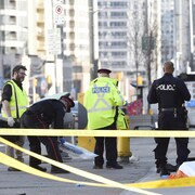 Des policiers torontois recueillent des objets près du corps d'une des victimes.