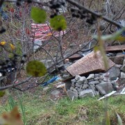 Des toiles, des vêtements, des morceaux de bois et des déchets sont abandonnés dans un boisé.