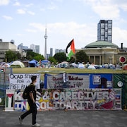 Un jeune homme passe devant le campement propalestinien au campus de l'Université de Toronto le 23 mai 2024.